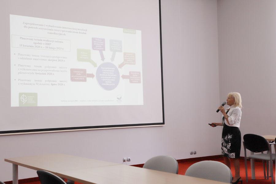 Przedstawicielka RDOS stoi koło ekranu z prezentacją i wskazuje na wyświetlane diagramy