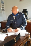 Komendant Wojewódzki Policji w Bydgoszczy nadinsp. Piotr Leciejewski siedzi przy stole i podpisuje umowę